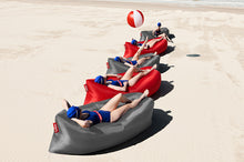 Load image into Gallery viewer, Girls Laying on Steel Grey and Red Fatboy Lamzac Version 3.0 Inflatable Loungers on the Beach