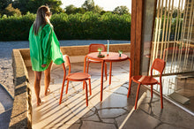 Load image into Gallery viewer, Lady Standing by Tangerine Fatboy Toni Chairs and Bistreau Table on a Patio
