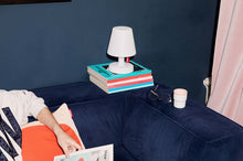 Load image into Gallery viewer, Fatboy Edison the Petit Lamp Sitting on Books on a Blue Couch
