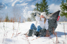 Load image into Gallery viewer, Girl Sitting on a Rock Grey Fatboy Bean Bag in the Snow
