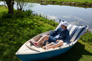 Guy Laying on a Stripe Ocean Blue Fatboy Original Slim Outdoor Bean Bag in a Boat