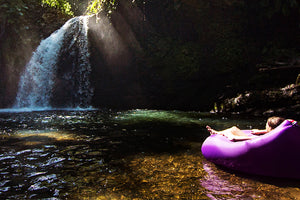 Girl Laying on a Purple Fatboy Lamzac the Original by a Waterfall