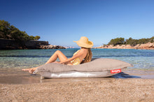 Load image into Gallery viewer, Model Sitting on a Grey Taupe Fatboy Floatzac on the Beach