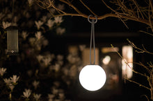 Load image into Gallery viewer, Taupe Fatboy Bolleke Lamp Hanging from a Tree Branch at Night
