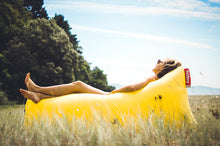 Load image into Gallery viewer, Girl Laying in a Yellow Fatboy Lamzac Lounger in a Field