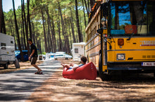 Load image into Gallery viewer, Guy Laying on a Red Fatboy Lamzac the Original by a Bus