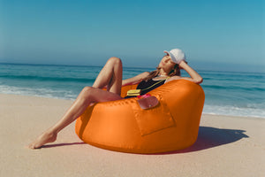Girl Sitting on an Orange Fatboy x Longchamp Chair on the Beach