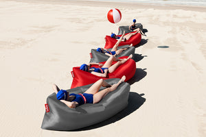 Girls Laying on Steel Grey and Red Fatboy Lamzac Version 3.0 Inflatable Loungers on the Beach