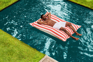 Guy Laying on a Red Stripe Fatboy Floatzac in a Pool
