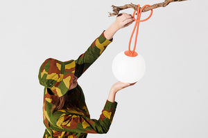 Lady Hanging a Tangerine Fatboy Bolleke Lamp from a Tree