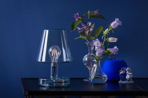 Blue Fatboy Transloetje Lamp Sitting on a Table Next to Flowers