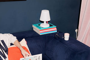 Fatboy Edison the Petit Lamp Sitting on Books on a Blue Couch