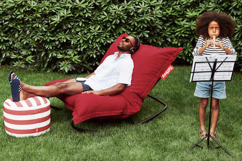 Guy Sitting on a Red Fatboy Original Slim Outdoor Bean Bag Rocker in the Grass