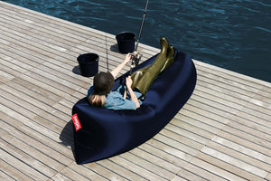 Girl Laying on a Dark Blue Fatboy Lamzac by the Water