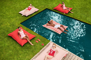Models Laying on Fatboy Original Outdoor Bean Bags Around a Pool