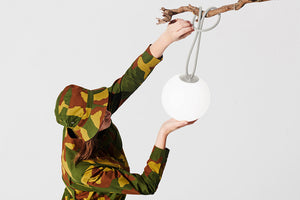 Model Hanging a Light Grey Fatboy Bolleke Lamp on a Tree Branch