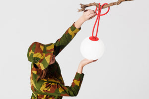 Model Hanging a Red Fatboy Bolleke Lamp on a Tree Branch