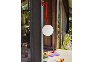 Red Fatboy Bolleke Lamp Hanging on a Hook Outside