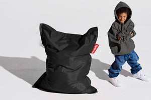 Boy Standing Next to a Black Fatboy Junior Bean Bag Chair